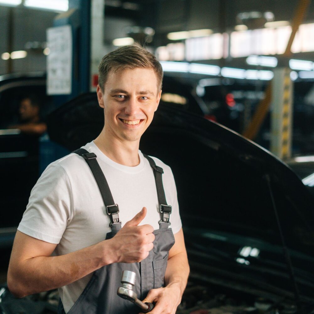 vertical-portrait-smiling-handsome-young-mechanic-male-wearing-uniform-holding-special-key